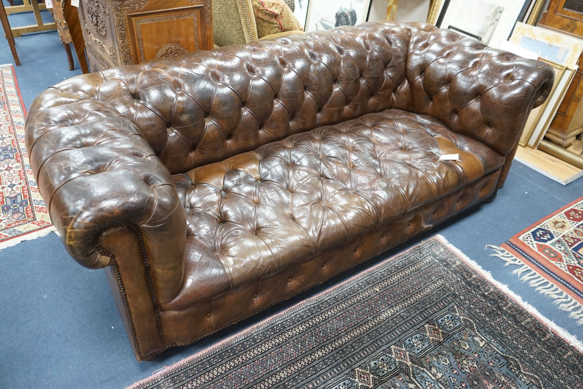 An early 20th century Chesterfield settee upholstered in deep buttoned brown leather, length 200cm, depth 90cm, height 72cm